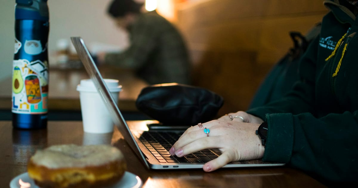 A person working at a laptop on a wooden table.