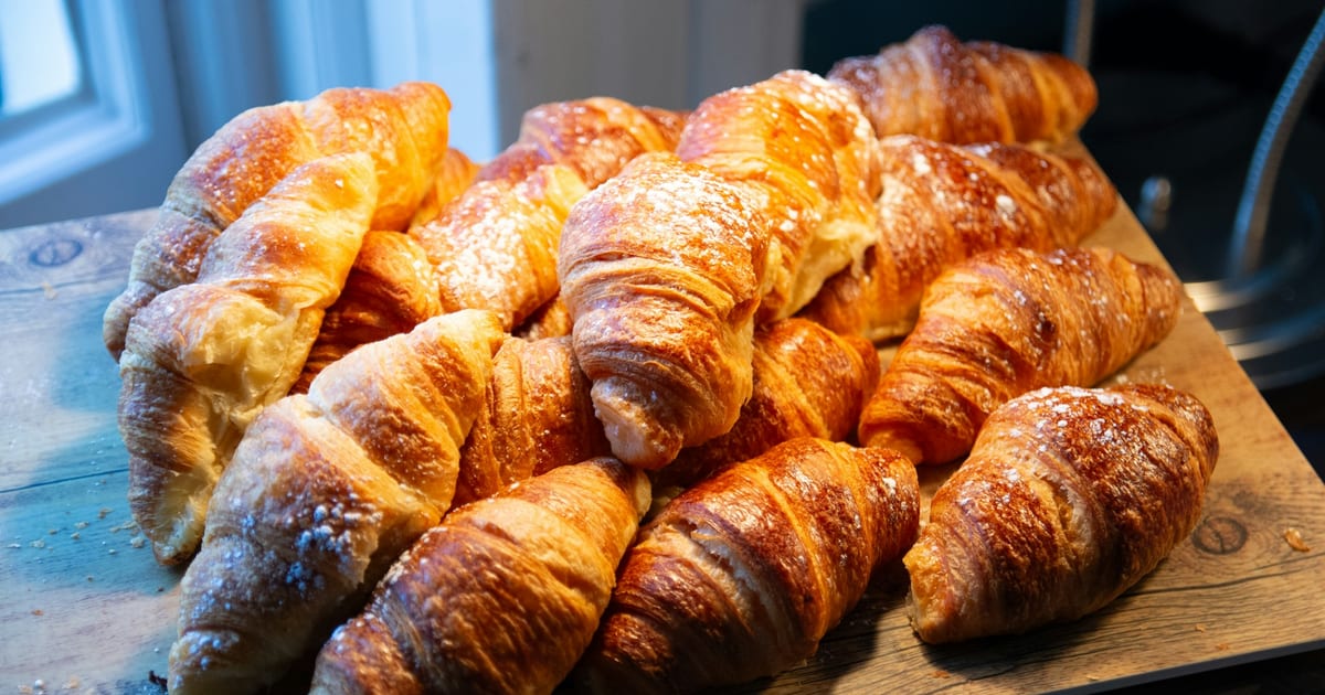 Freshly baked croissants piled on a wooden surface.