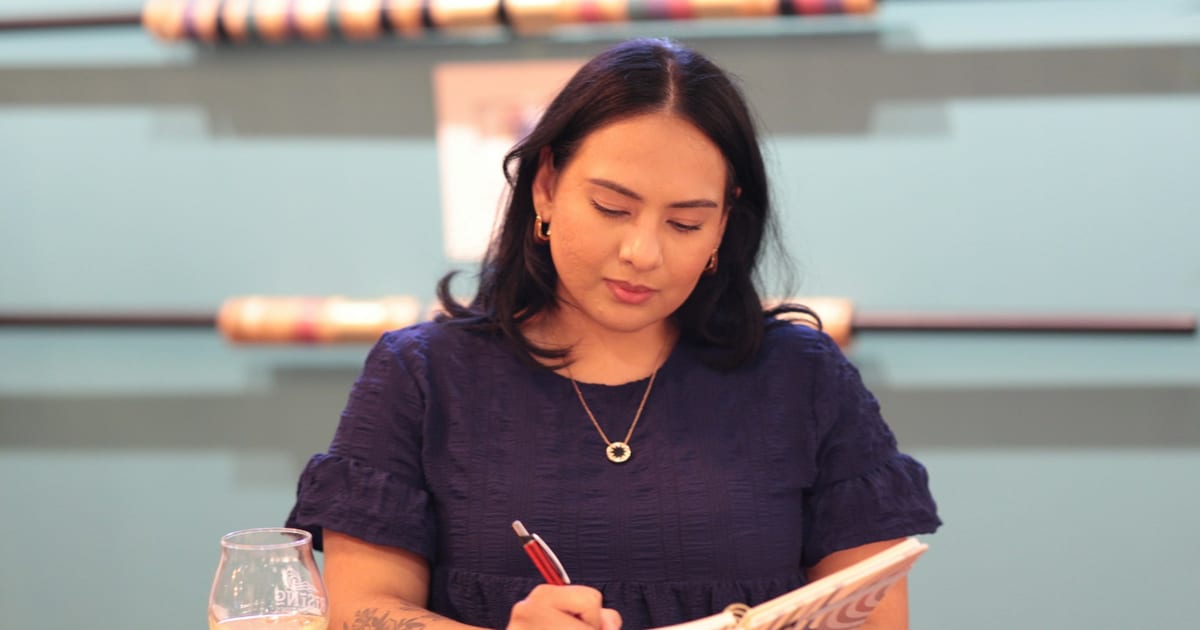 A small business owner writing notes in a notebook at the shop counter.