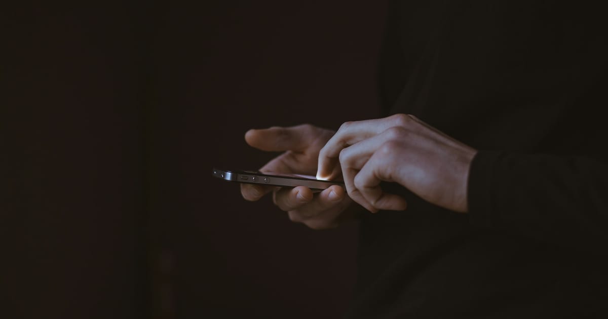 A silhouetted figure holding up a smartphone.