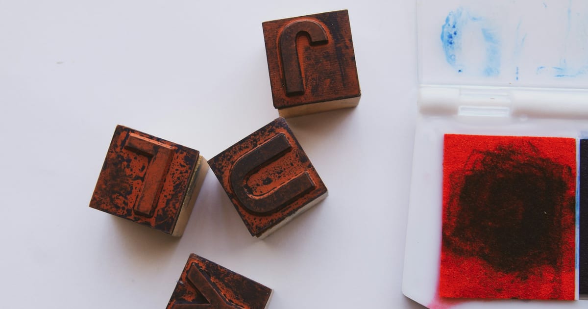 Wooden letterpress stamp blocks sitting next to an open red ink pad.