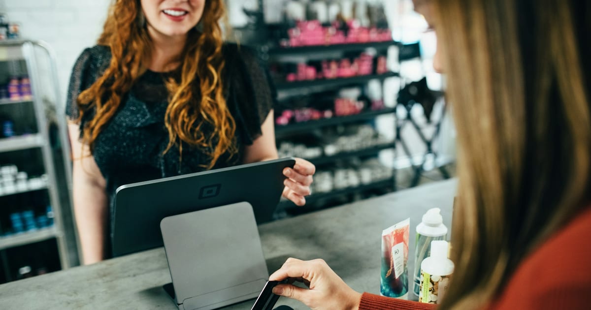A customer holding a payment card at a shop counter.