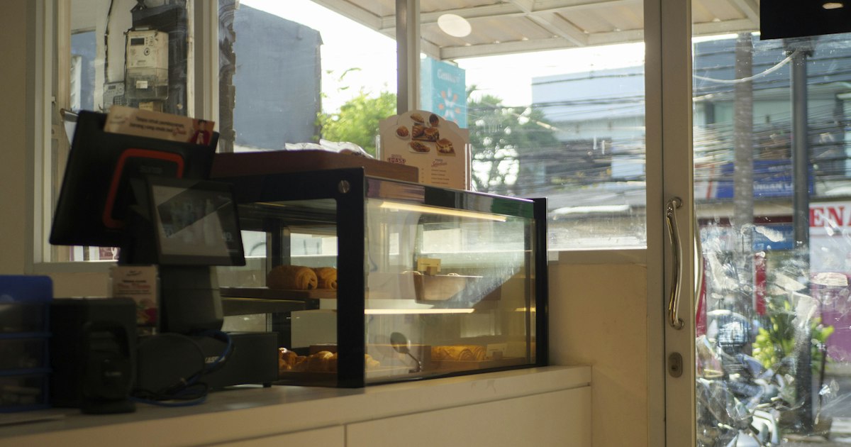 A counter-top sign beside a display case in a small shop.