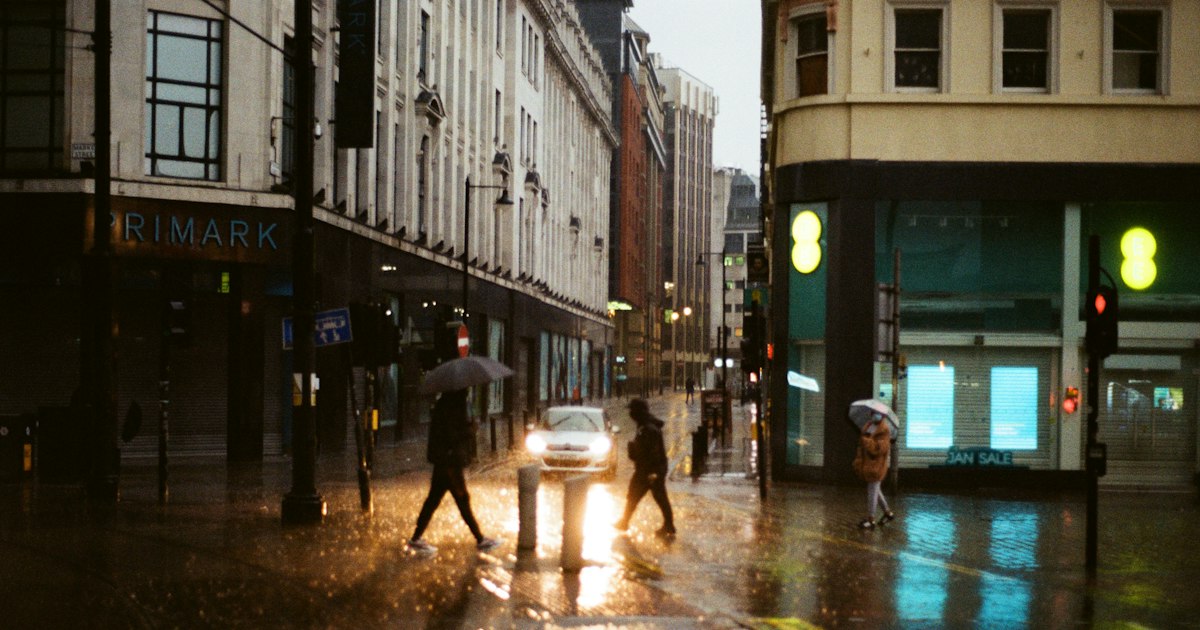 People crossing a wet street under umbrellas on a gray winter afternoon.