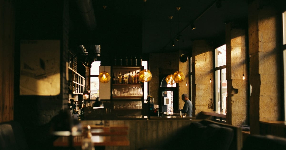 A dimly lit restaurant with empty tables and chairs.