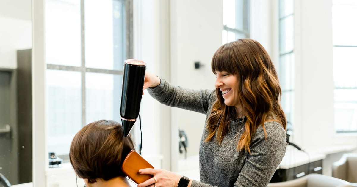A stylist holding a hair dryer in a salon.