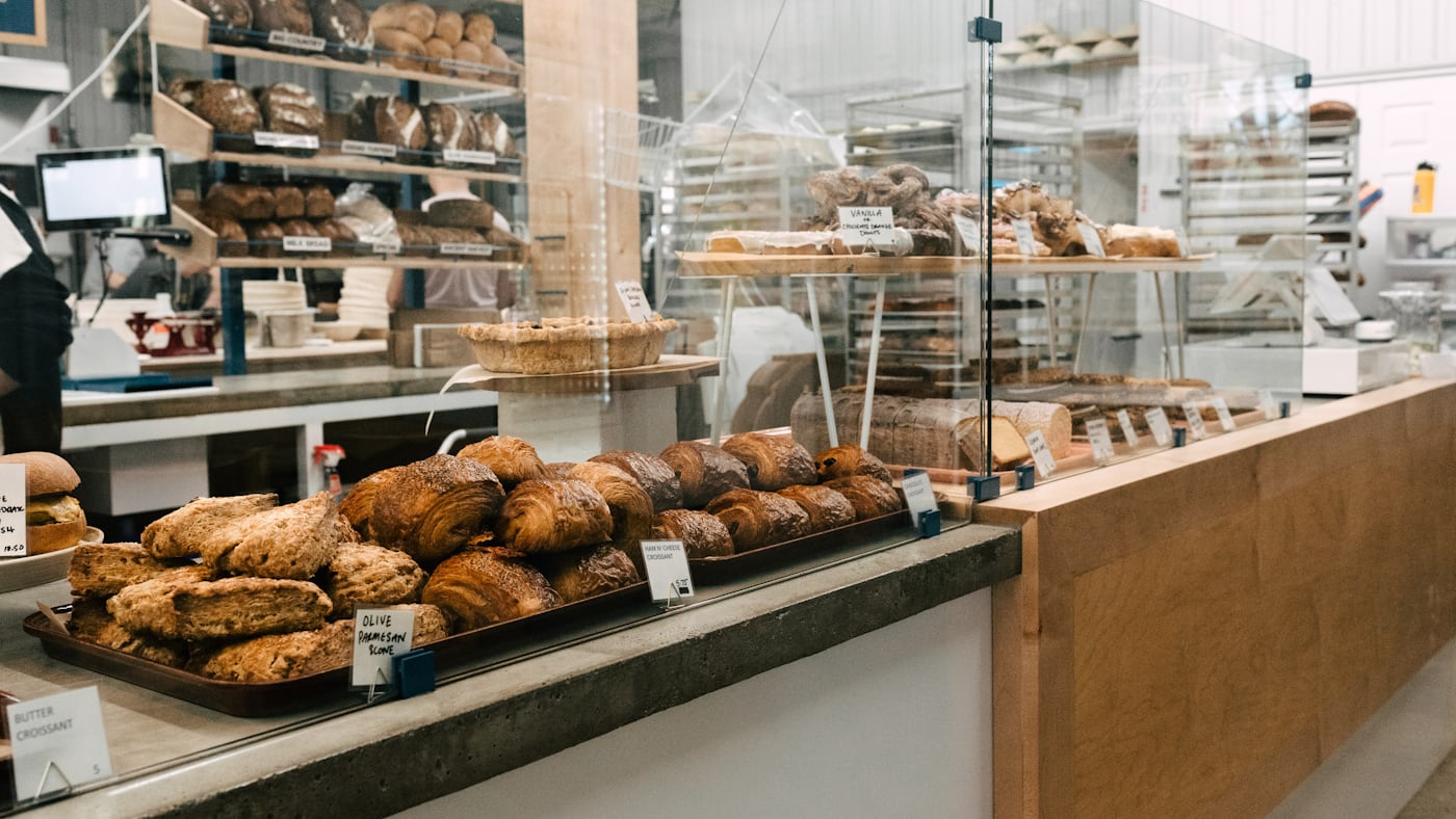 A bakery counter lined with trays of fresh bread and pastries.