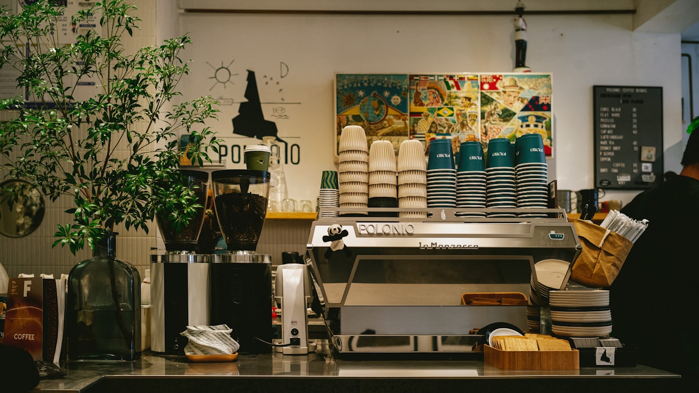 The counter of a small independent coffee shop, with an espresso machine and cups ready for service.