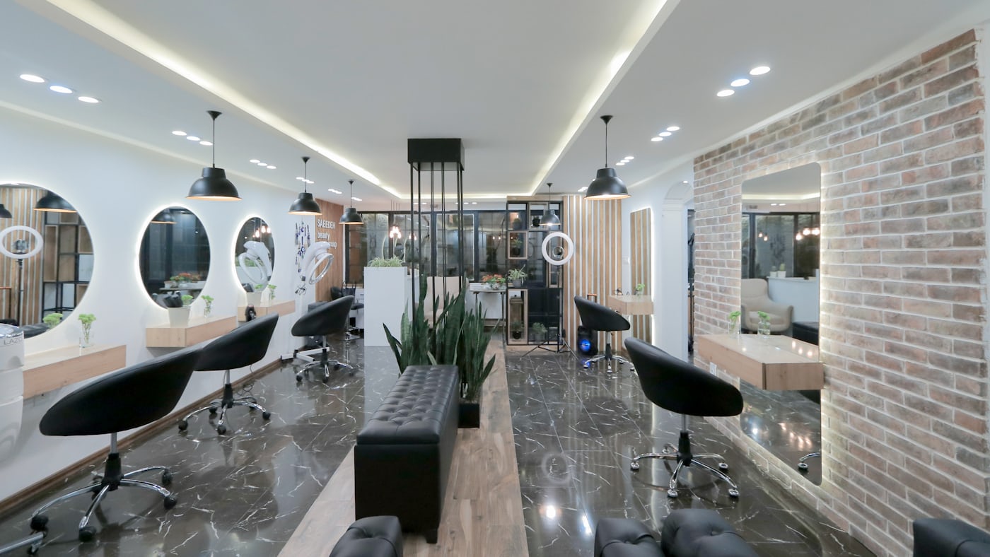 A hair salon with styling chairs and round mirrors along a brick wall.