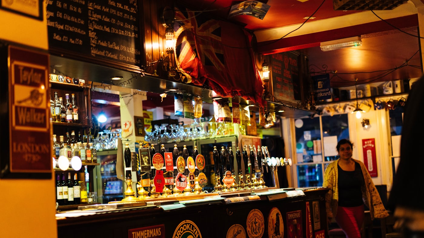 A busy pub bar lined with taps and bottles.