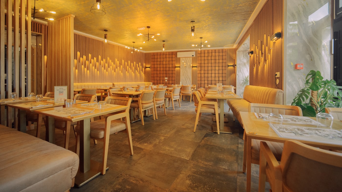 A small restaurant dining room with wooden tables under warm lighting.